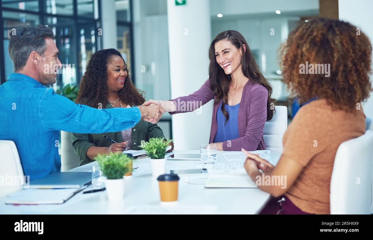 Hai lavorato sodo per raggiungere questa promozione. due designer che scuotono le mani durante una riunione. Foto Stock