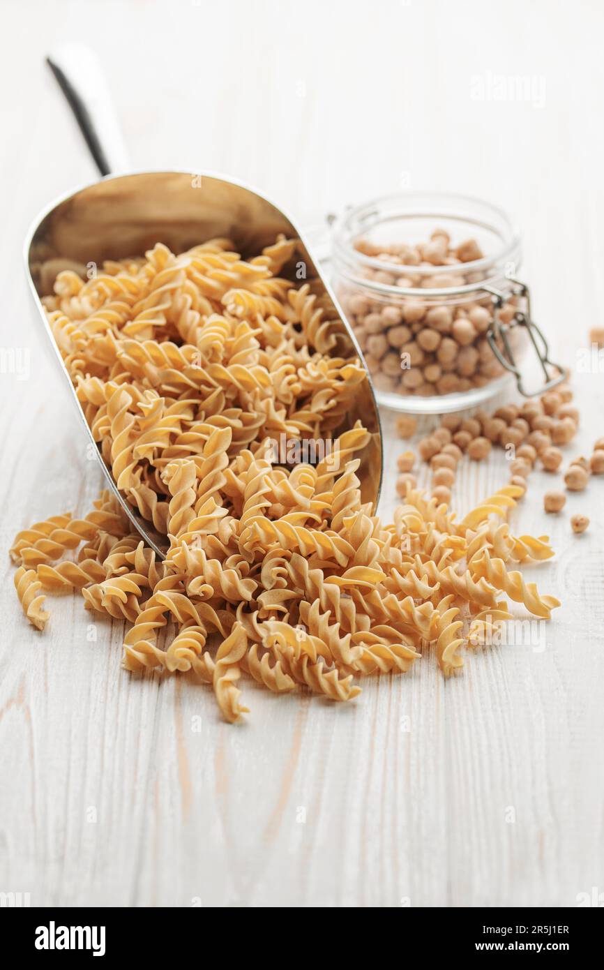 Fusilli di ceci su fondo ligneo. Tritare con pasta cruda e ceci. Pasta senza glutine. Foto Stock