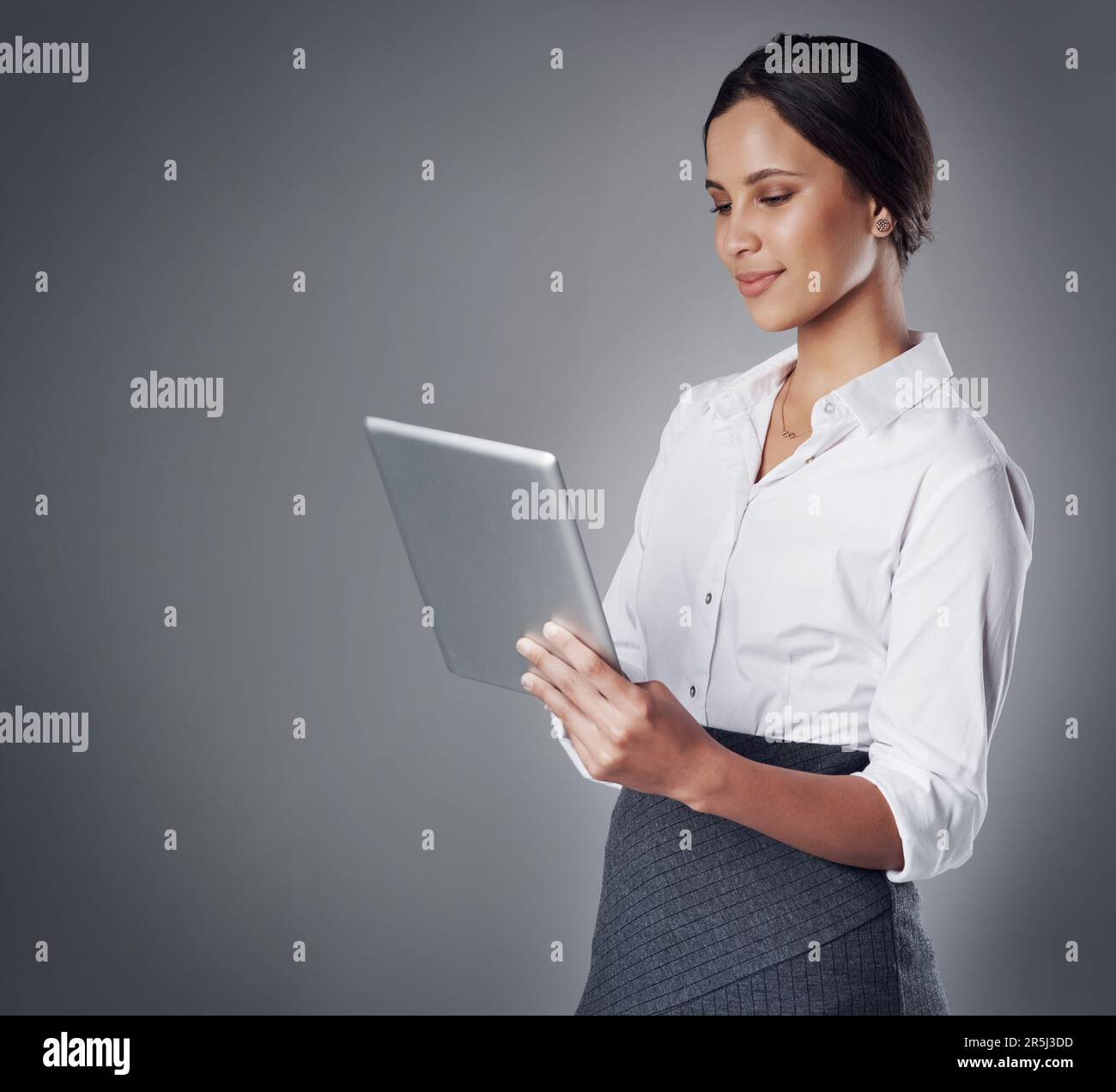 Stare al passo con il business competitivo utilizzando tecnologie all'avanguardia. Studio di una giovane donna d'affari che utilizza un tablet digitale contro un grigio Foto Stock