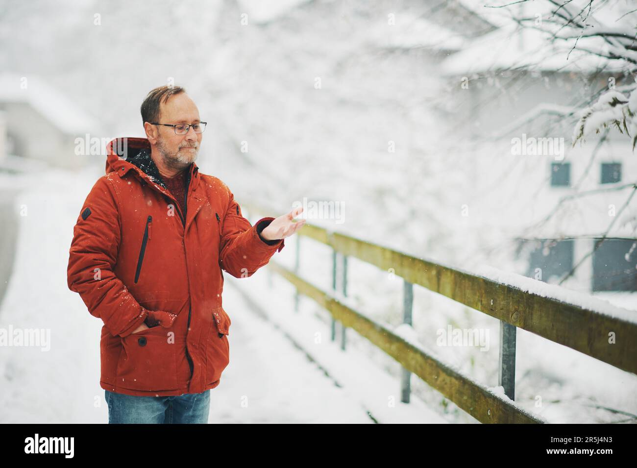 Ritratto all'aperto dell'uomo di mezza età, 55 - 60 anni, piacevole giornata fredda, indossando una giacca invernale rossa arancione Foto Stock