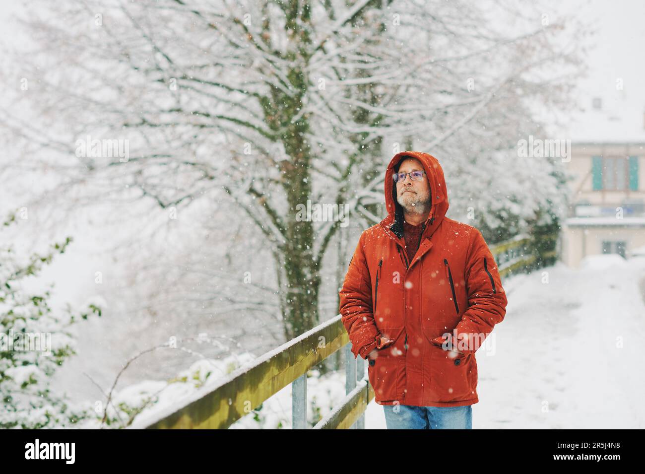 Ritratto all'aperto dell'uomo di mezza età, 55 - 60 anni, piacevole giornata fredda, indossando una giacca invernale rossa arancione Foto Stock