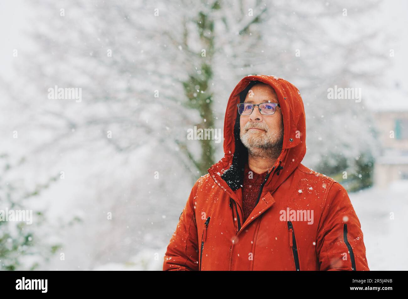 Ritratto all'aperto dell'uomo di mezza età, 55 - 60 anni, piacevole giornata fredda, indossando una giacca invernale rossa arancione Foto Stock