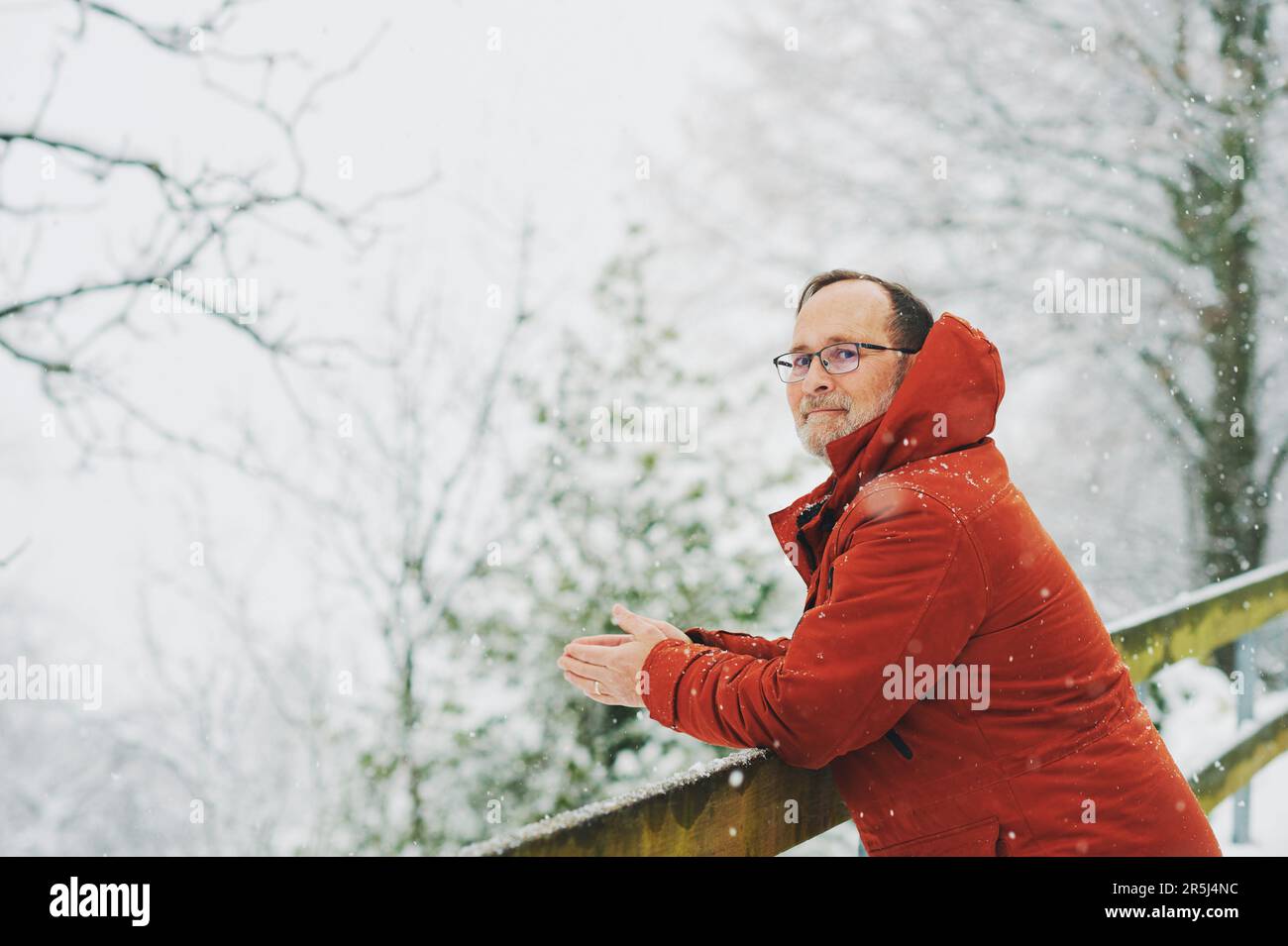 Ritratto all'aperto dell'uomo di mezza età, 55 - 60 anni, piacevole giornata fredda, indossando una giacca invernale rossa arancione Foto Stock