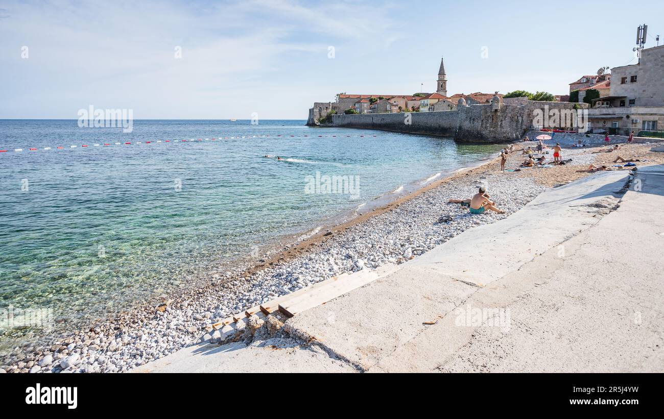 I gradini conducono alla spiaggia di Pizana, vicino alla città vecchia di Budva, punteggiata di soleggiatori che si godono il sole di inizio estate nel maggio 2023. Foto Stock