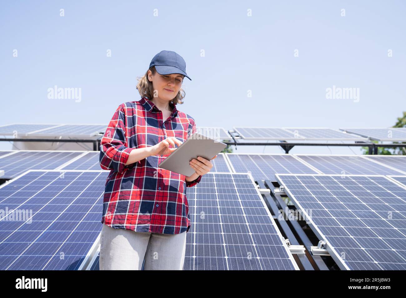 Donna con tablet digitale sullo sfondo di una centrale solare mobile. Foto Stock