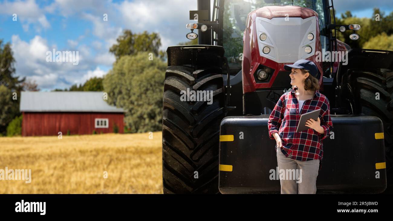 Donna contadina con un tablet digitale sullo sfondo di un trattore agricolo Foto Stock