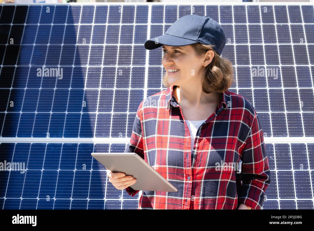 Donna con tablet digitale sullo sfondo di una centrale solare mobile Foto Stock