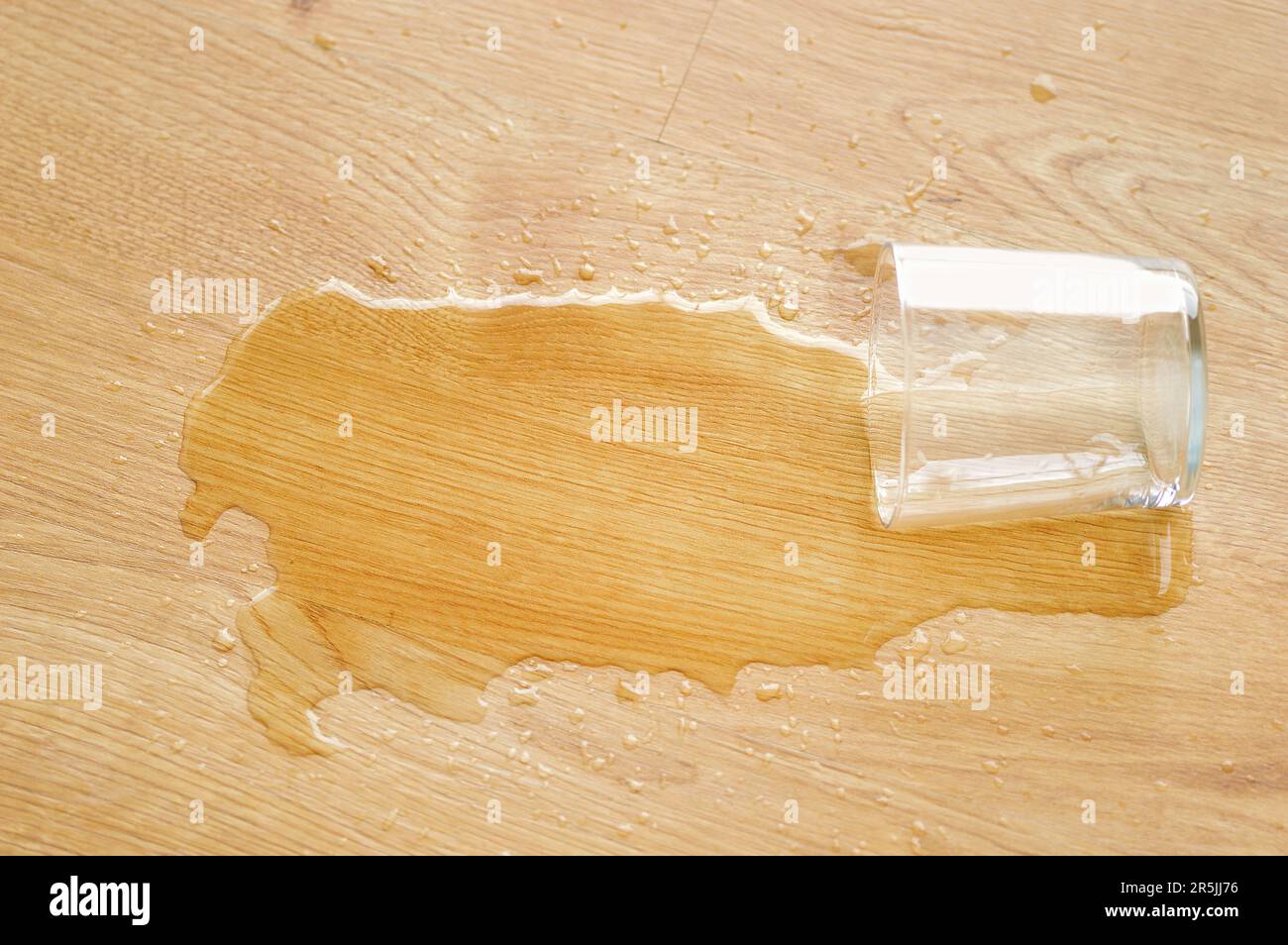 parquet in legno laminato con un bicchiere d'acqua sulla superficie Foto Stock