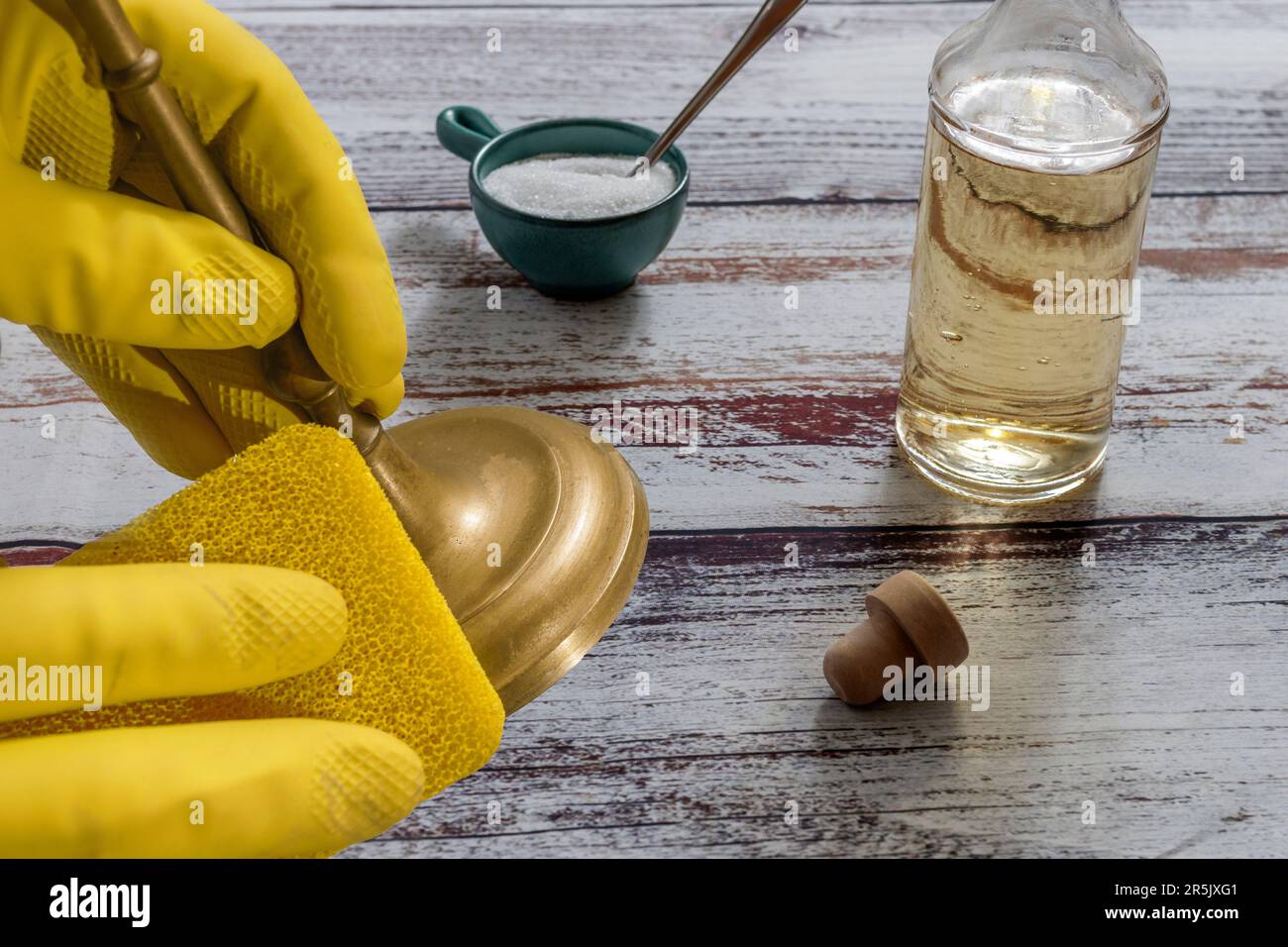 Ragazza con guanti gialli che pulisce un candelabro di ottone con aceto,  sale e una spugna gialla Foto stock - Alamy