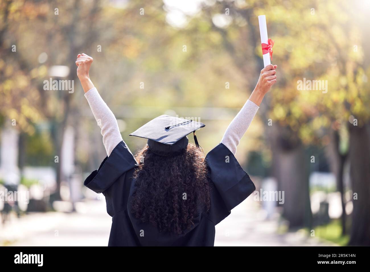 Laurea, studentessa di ritorno e donna che celebra il successo accademico o che ha conseguito il diploma o la vittoria presso il campus universitario con un favore. Motivazione Foto Stock