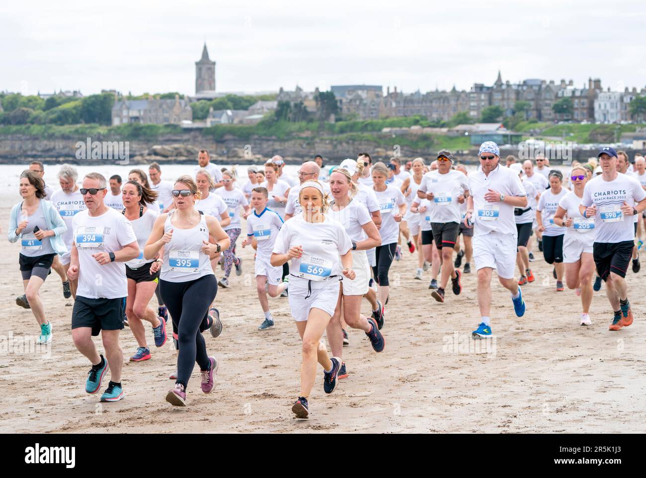 I corridori, che indossano il bianco, gareggiano nella gara annuale dei carri di fuoco lungo la West Sands Beach a St Andrews, Fife. La gara del 5km prende parte nello stesso luogo in cui è stata girata la famosa scena di corsa del film del 1981 carri di fuoco. I proventi dell'evento sono donati all'RNLI e alle associazioni di beneficenza locali. Data immagine: Domenica 4 giugno 2023. Foto Stock