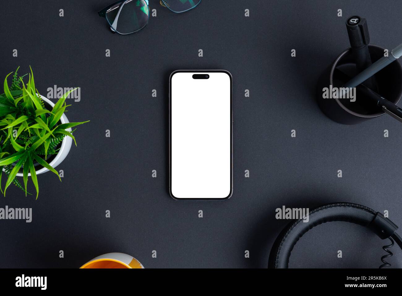 Telefono mockup sulla scrivania nera. Schermo isolato in bianco per la promozione del design delle app. Vista dall'alto, composizione di giacitura piatta Foto Stock