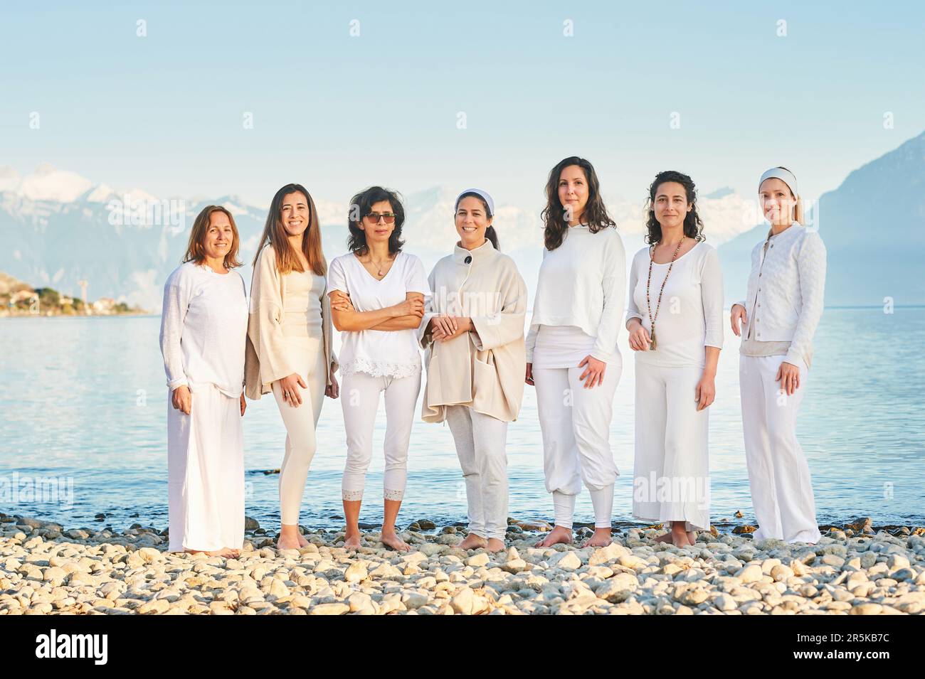 Ritratto di gruppo di belle donne che si posano all'esterno con un bellissimo paesaggio montano sullo sfondo, indossando abiti bianchi Foto Stock