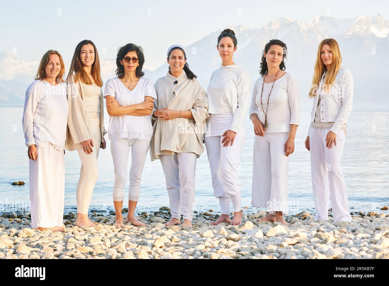 Ritratto di gruppo di belle donne che si posano all'esterno con un bellissimo paesaggio montano sullo sfondo, indossando abiti bianchi Foto Stock