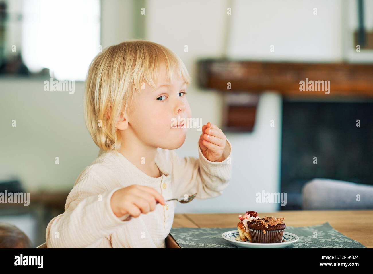 Simpatico bambino che mangia cupcakes per dessert, snack dolci Foto Stock