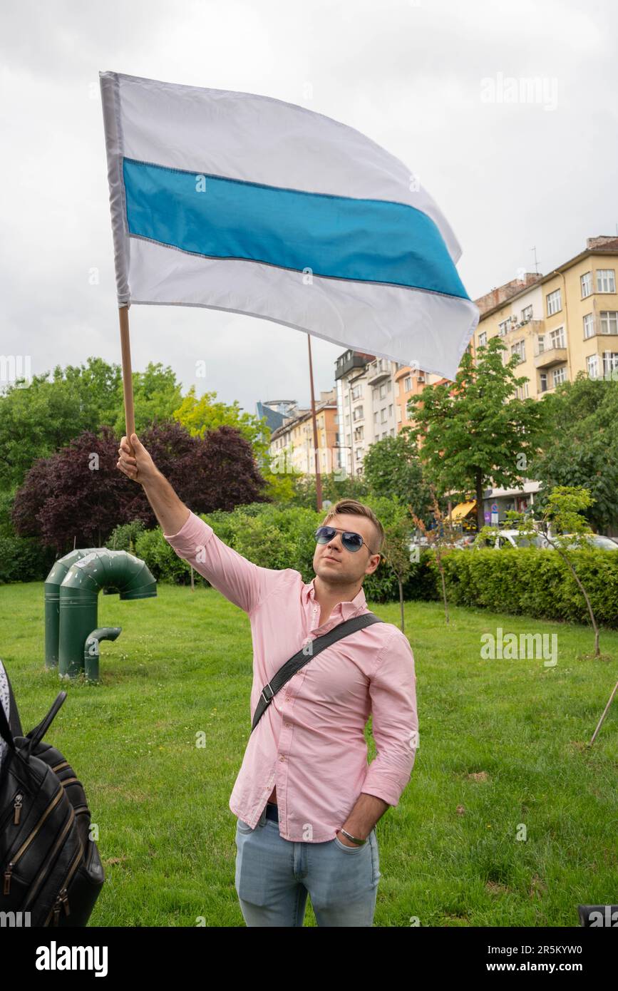Un uomo è in piedi con una bandiera di opposizione russa in un incontro a sostegno di Alexei Navalny a Sofia, Bulgaria Foto Stock