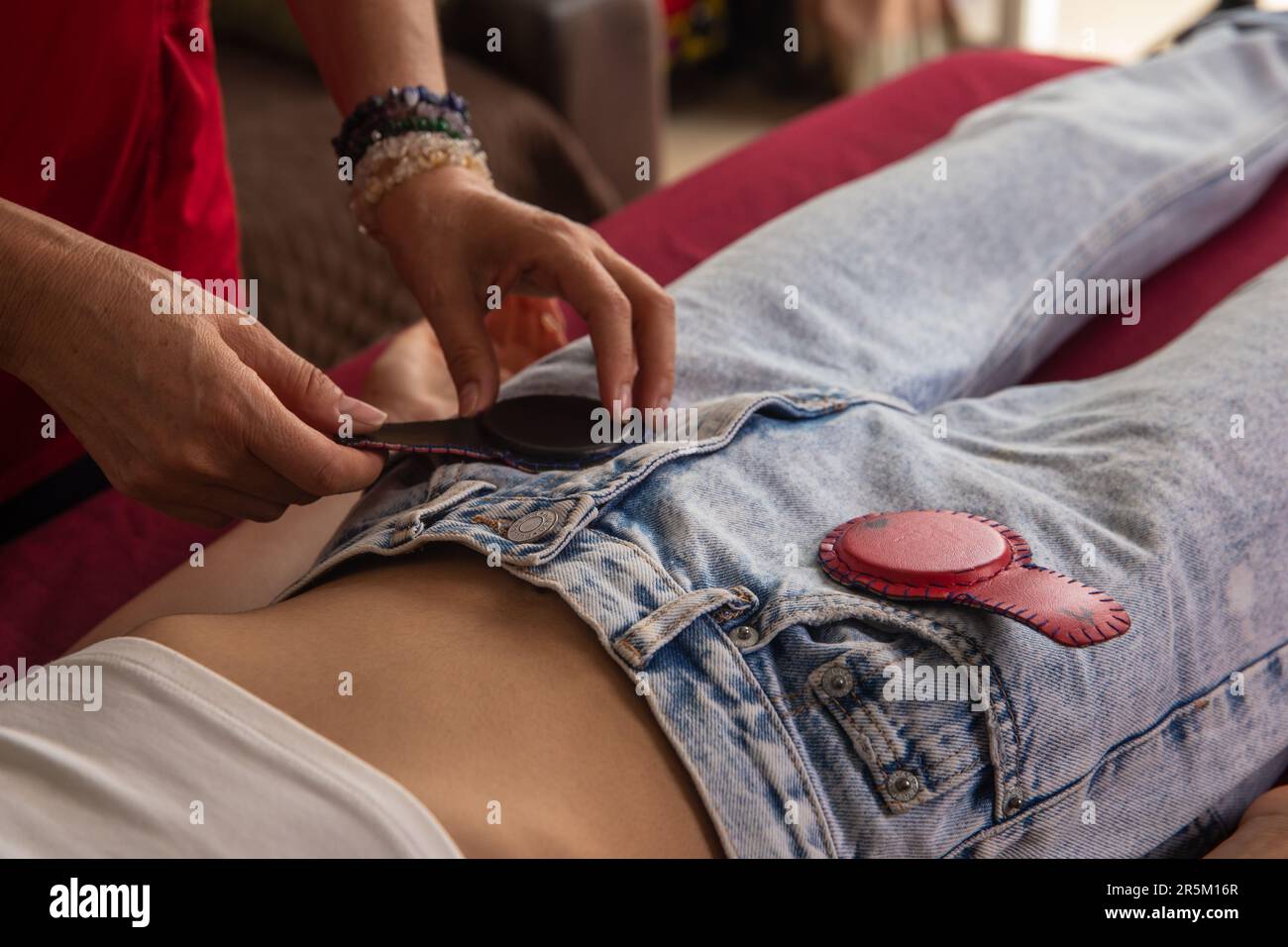 giovane donna sdraiata sul letto di massaggio che riceve la terapia olistica con i magneti, la fotografia di dettaglio, la terapia medica di biomagnetismo Foto Stock