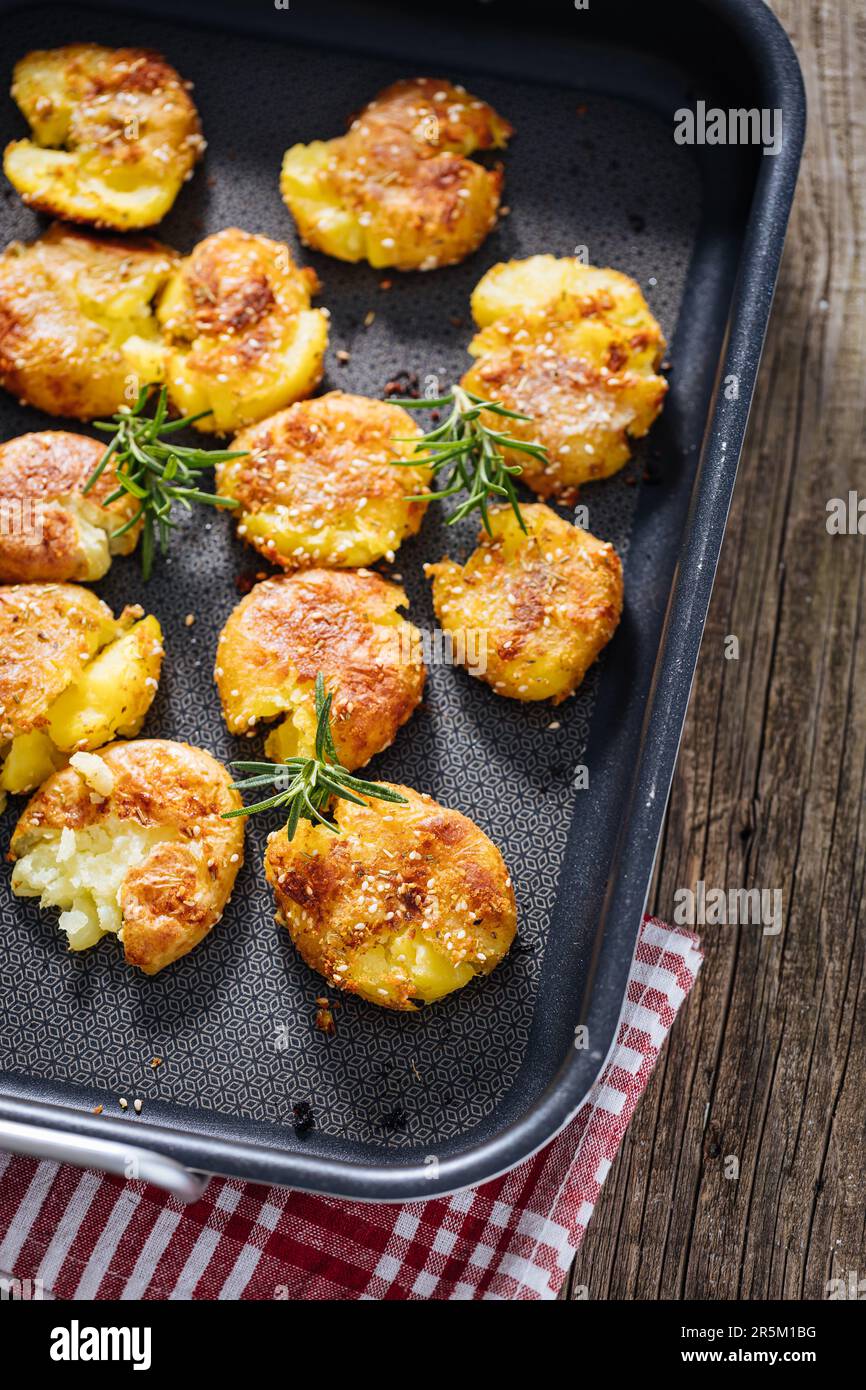 Patate al forno o arrosto in vassoio di metallo condito con rosmarino e sale e pepe. Dorato e croccante. Foto Stock