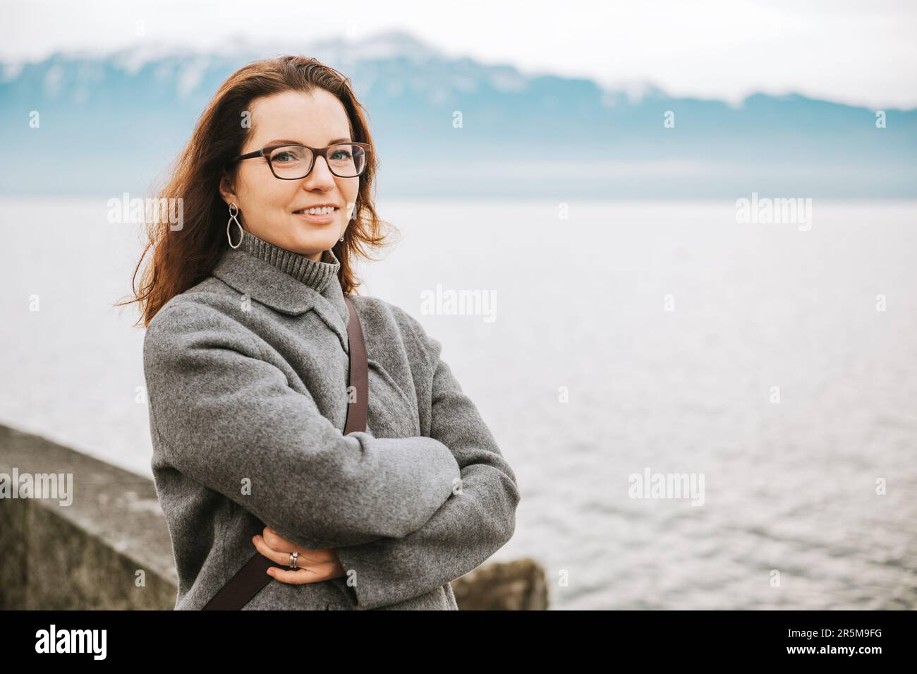 Ritratto all'aperto di bella donna, vestito di grigio, in posa accanto al lago Foto Stock