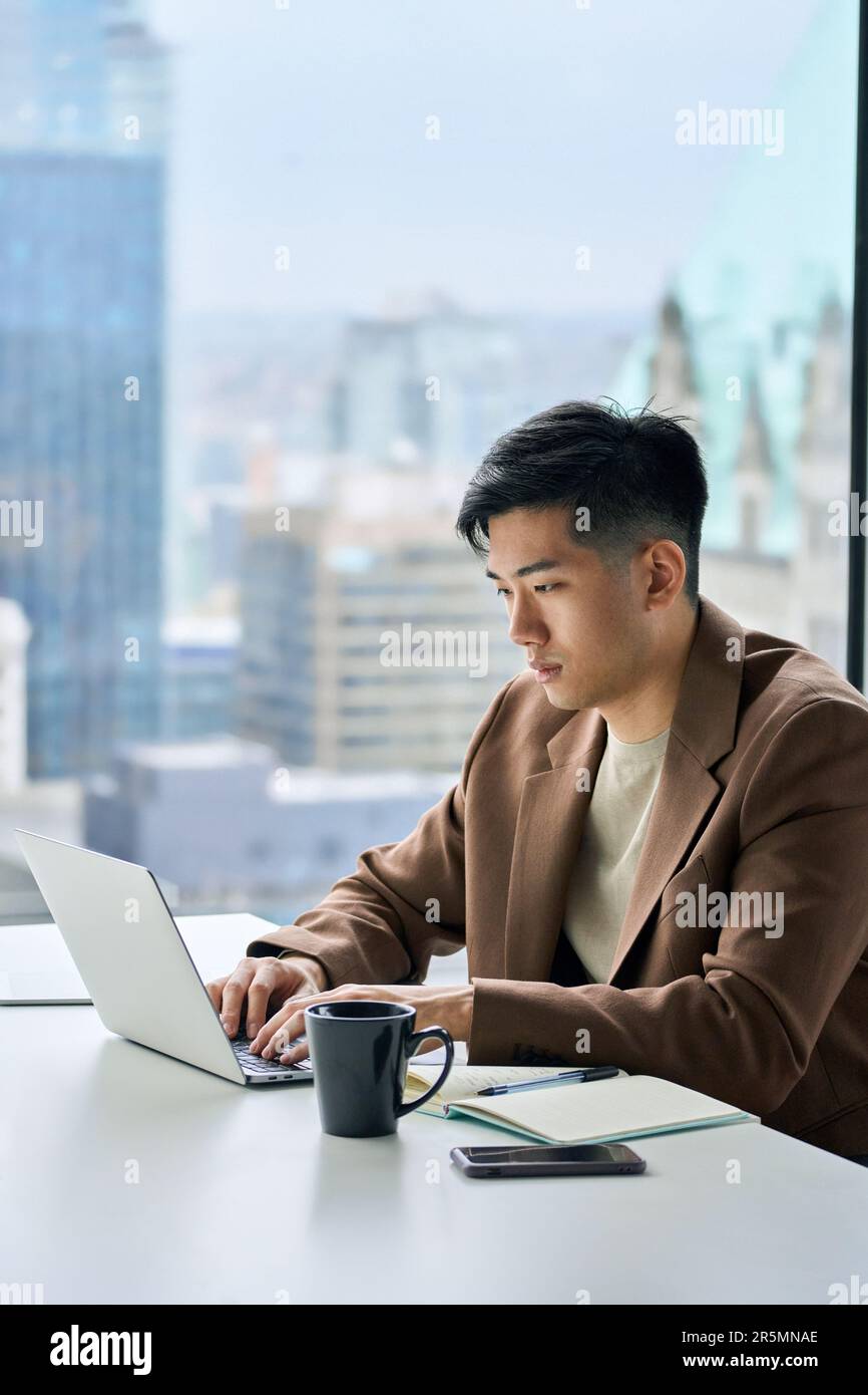 Giovane uomo d'affari asiatico impegnato che lavora su un computer portatile in ufficio. Foto Stock