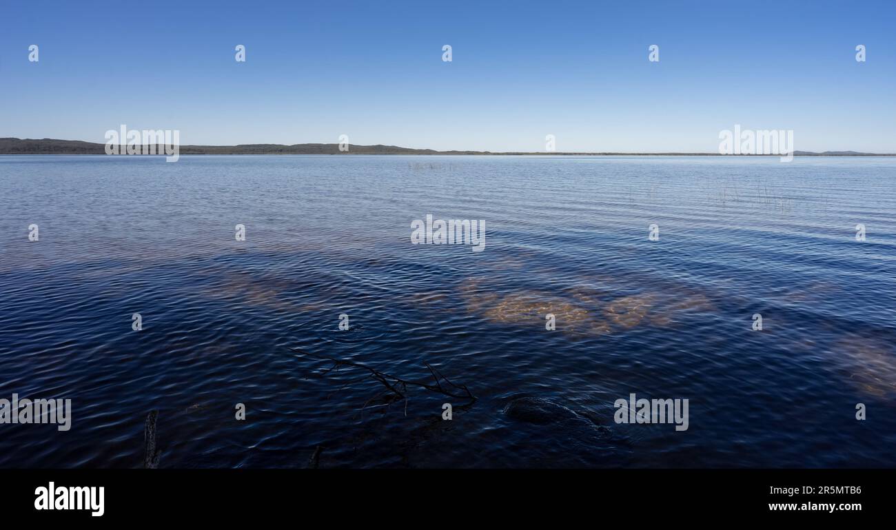 Calma lago sfondo paesaggio immagine con acqua blu, cielo blu, copia spazio per concetto di serenità, pace, relax, calma Foto Stock