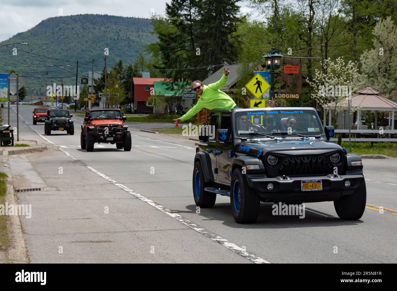 Quattro veicoli Jeep Wrangler sulla strada in Speculator, NY USA parte di un gruppo che visita le montagne Adirondack con un pilota appeso fuori dal veicolo Foto Stock
