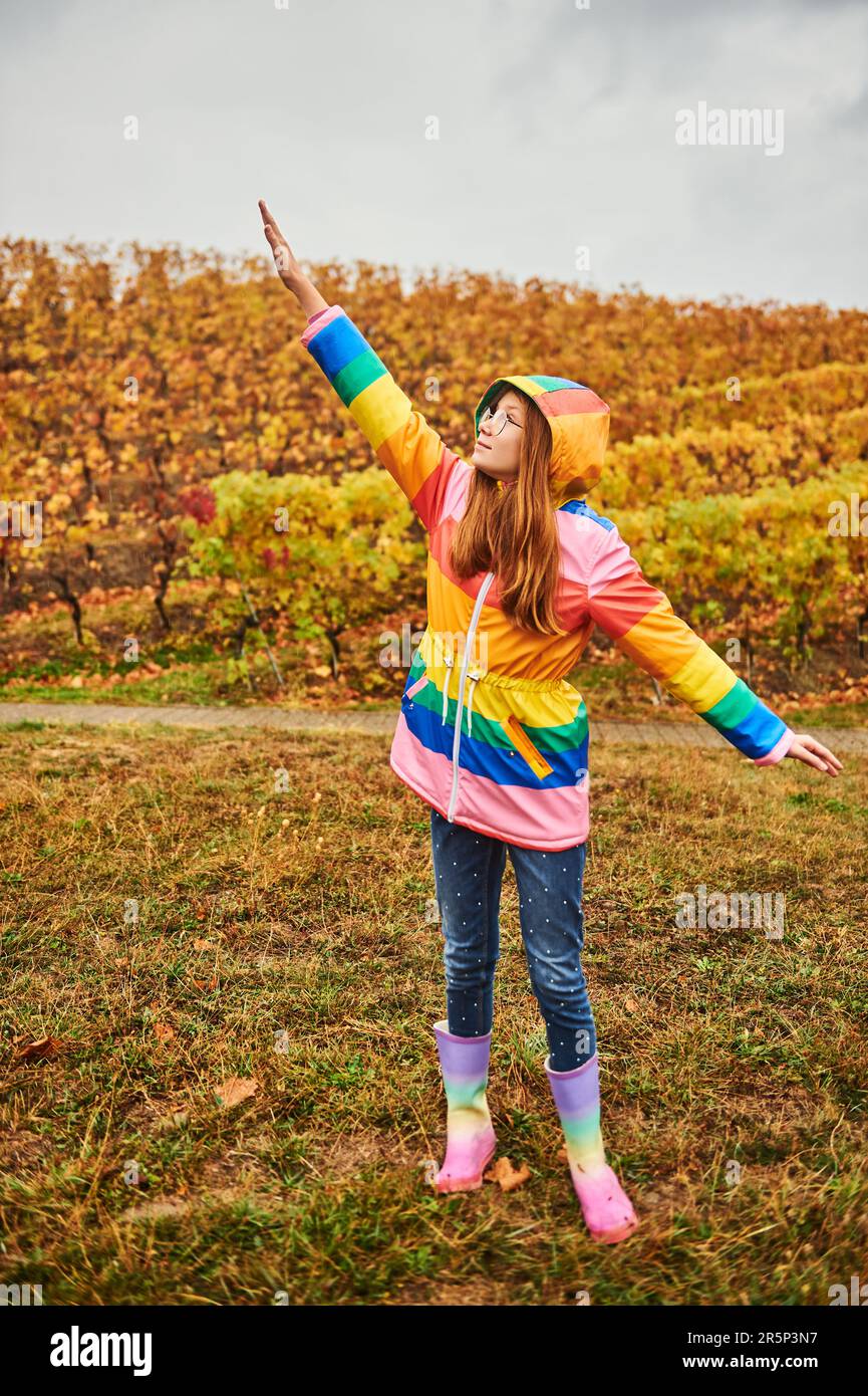 Ritratto all'aperto di bella ragazza giovane indossando cappotto pioggia colorato Foto Stock