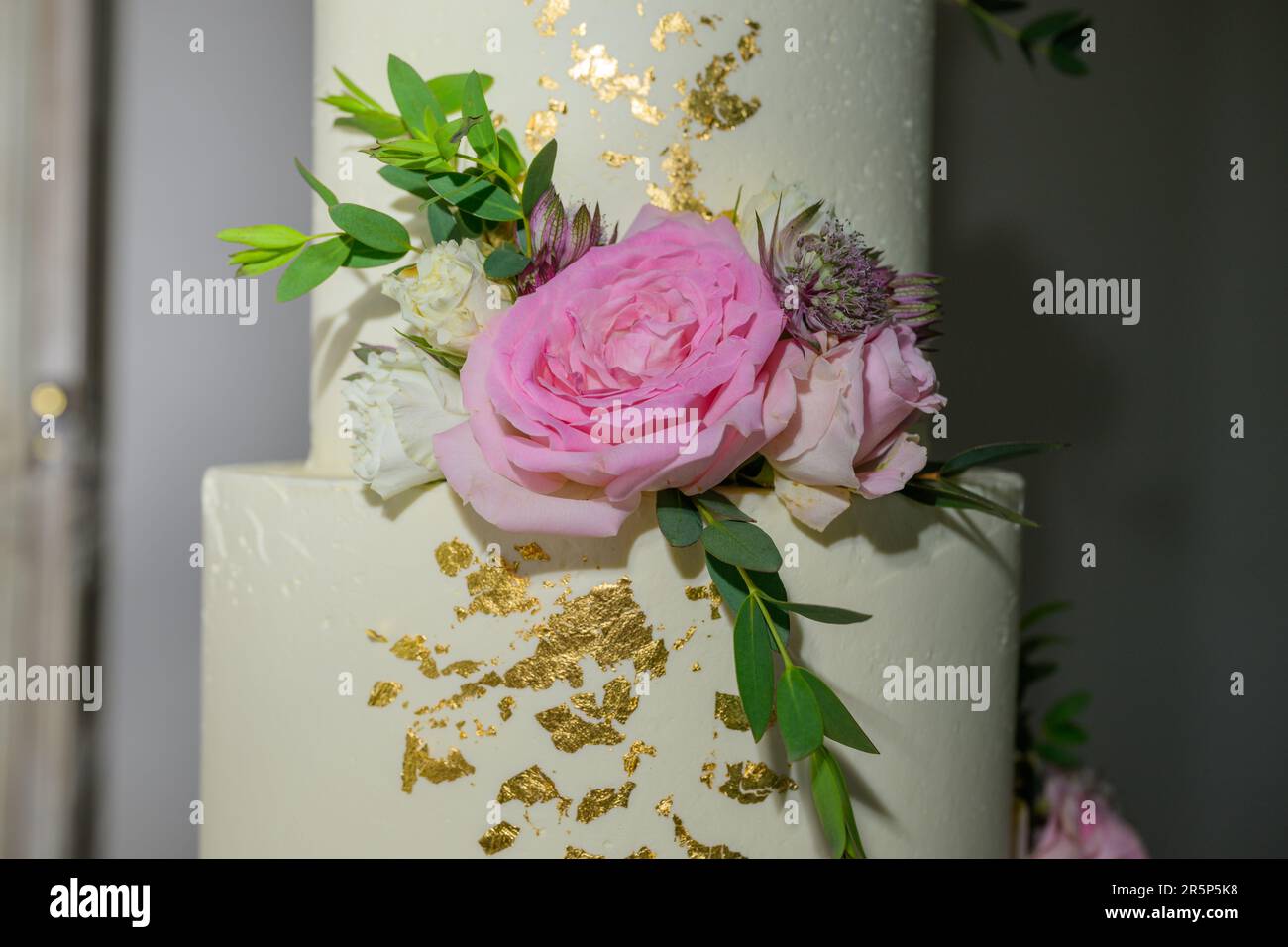 Torta nuziale a quattro livelli con fiori freschi e foglia d'oro Foto Stock