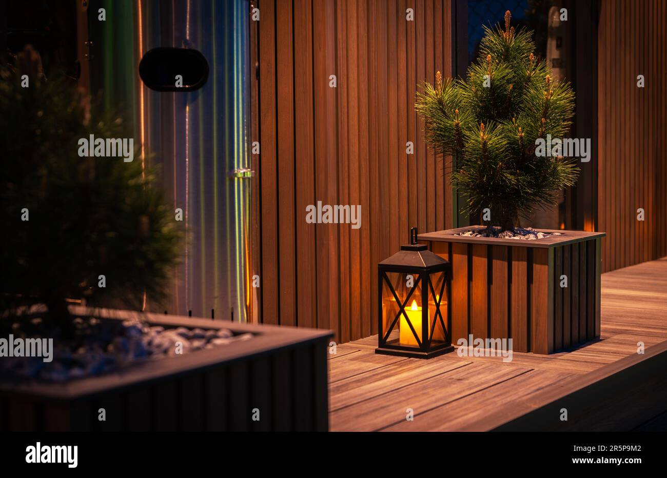Moderno giardino residenziale elementi decorativi. Composto fatto Garden Shed e una Pot. Illuminazione notturna. Foto Stock
