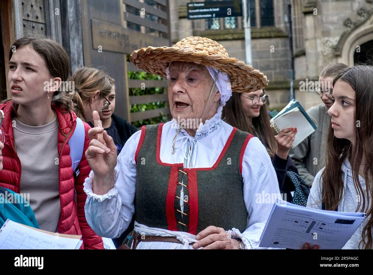 Guida turistica del Regno Unito. Donna in costume Tudor tradizionale con studenti stranieri in un corso di scoperta dei fatti di storia educativa. Stratford Upon Avon, Inghilterra Foto Stock