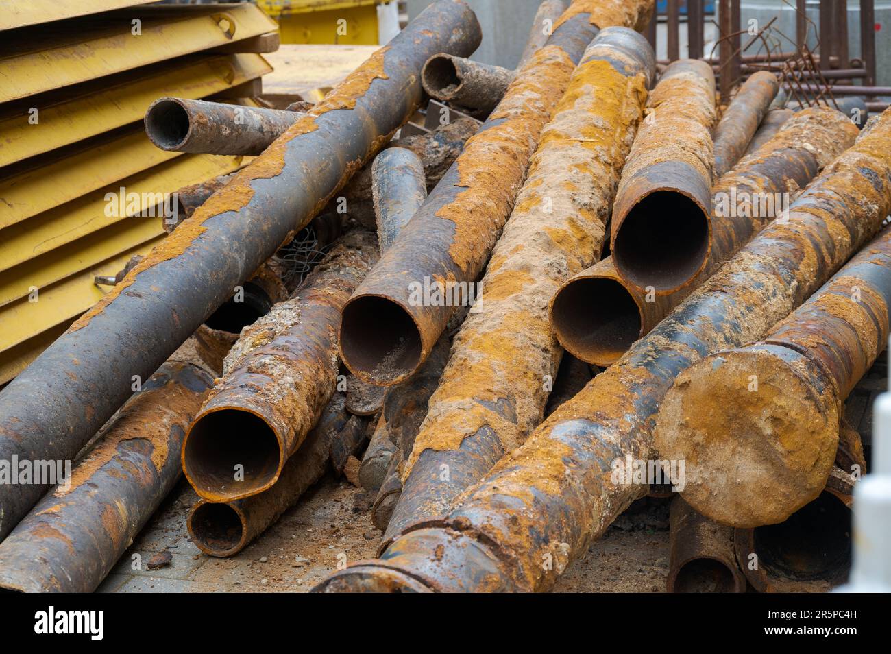 Cumulo di vecchi tubi di alghe arrugginiti giacenti sul cantiere Foto Stock