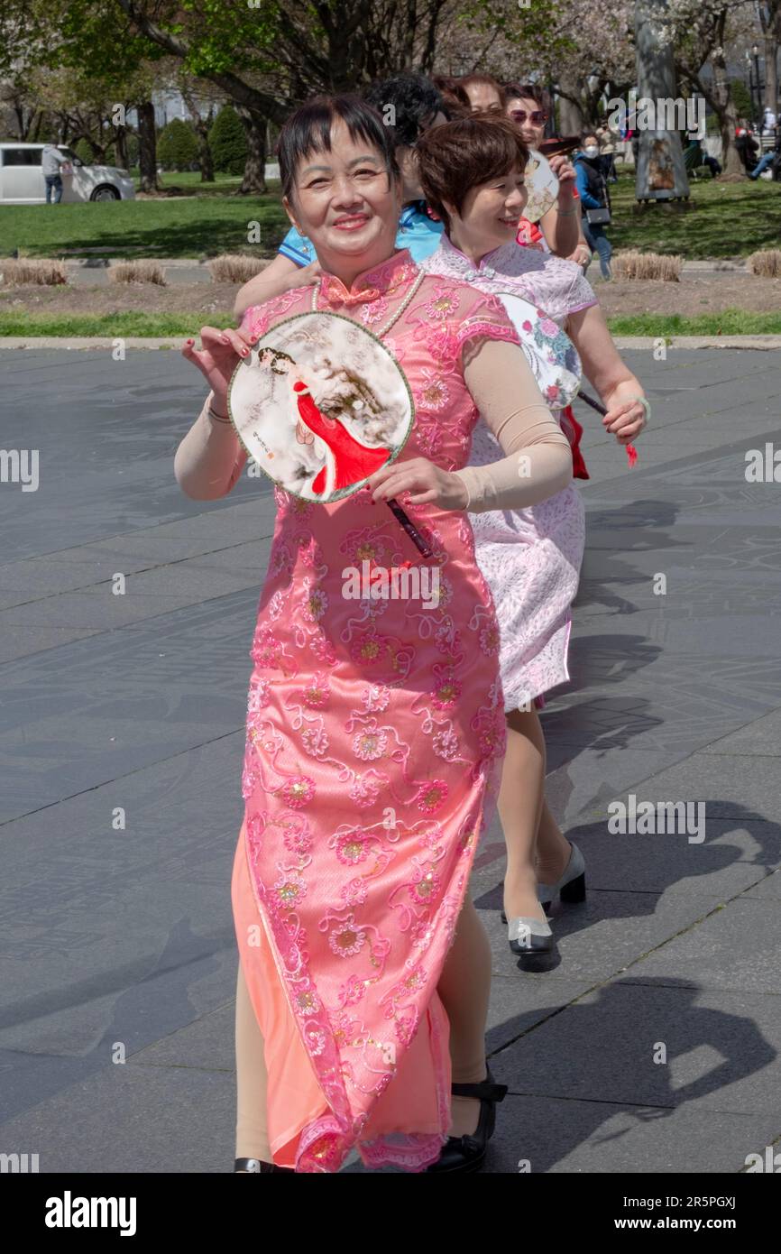 Un gruppo di cinesi americani di mezza età in abiti colorati e con i fan pratica le routine di danza nel Flushing Meadows Corona Park nel Queens, New York. Foto Stock