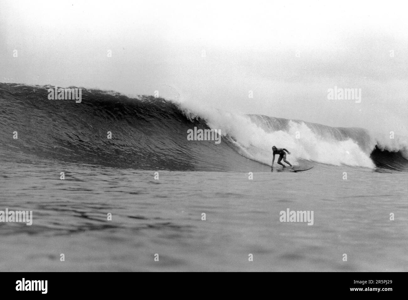 Surfista accovacciato nel suo turno, si prepara per una grande onda a Crab Island, Langland, Gower, Galles. Fotografia in bianco e nero di Phil Holden Foto Stock