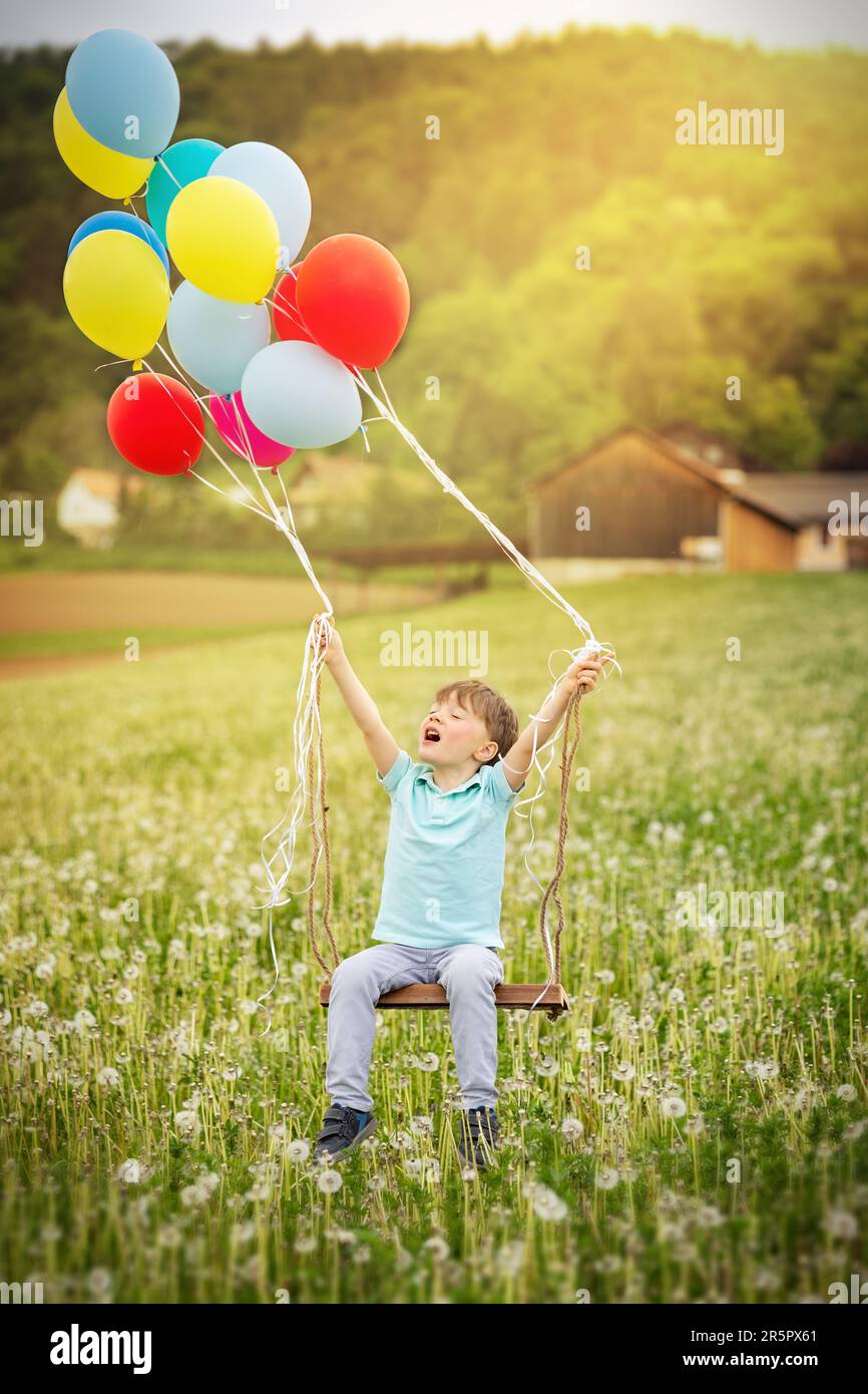 le altalene sono sollevate da palloncini nel cielo Foto Stock