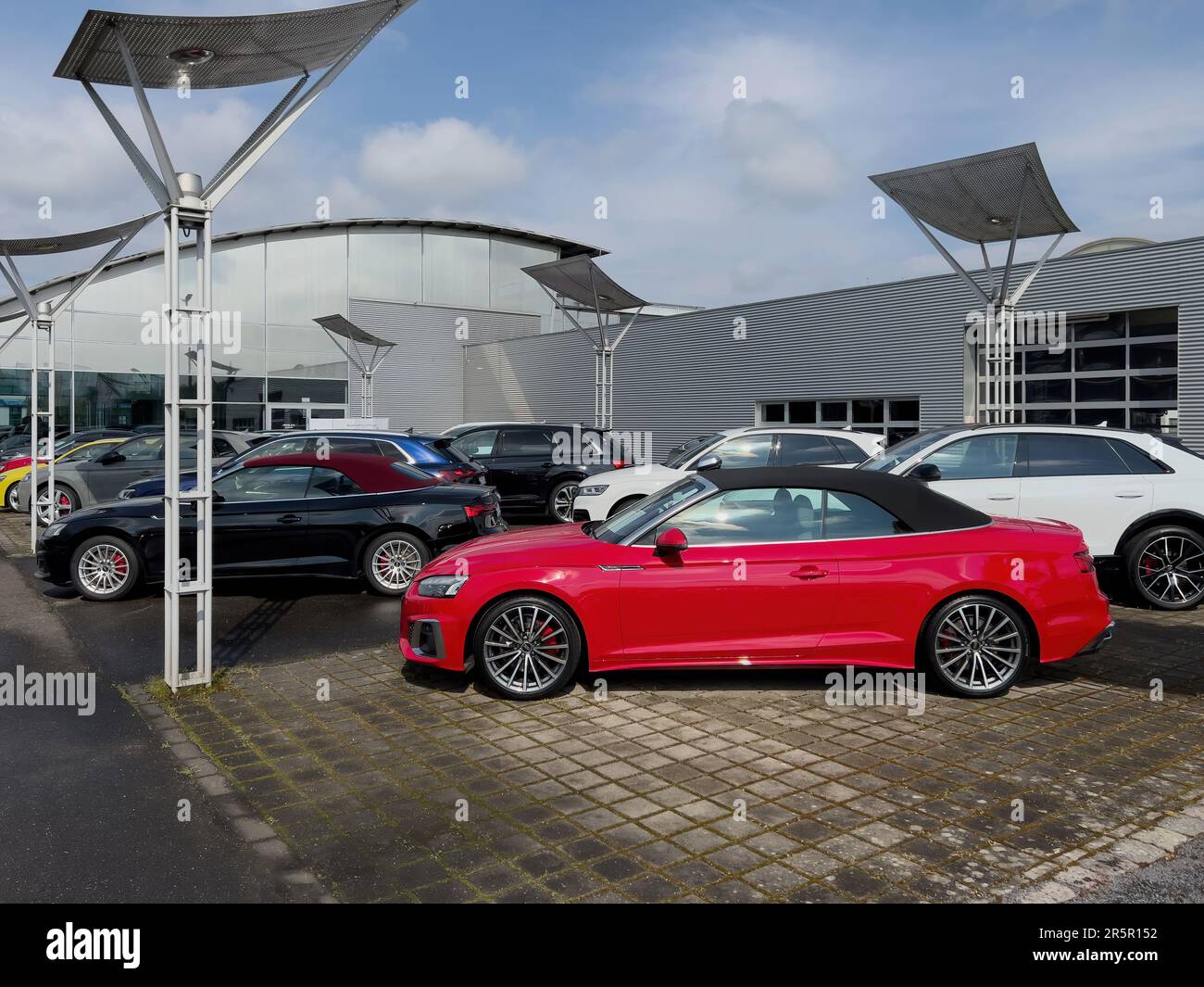 Germania - 1 maggio 2023: Una lussuosa vettura sportiva rossa si trova all'esterno di uno showroom della concessionaria tedesca. Il suo elegante telaio cabrio e il potente motore lo rendono la scelta ideale per gli appassionati di auto e gli amanti del lusso Foto Stock