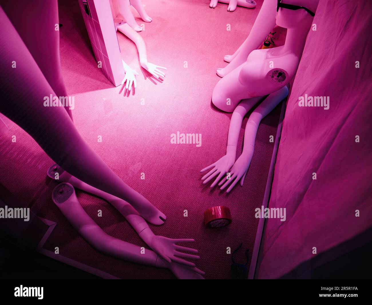 Manichini danneggiati in un negozio di moda rappresentano il concetto di moda veloce, con modelli rotti e sfigurati con tonalità di colore magenta. Foto Stock