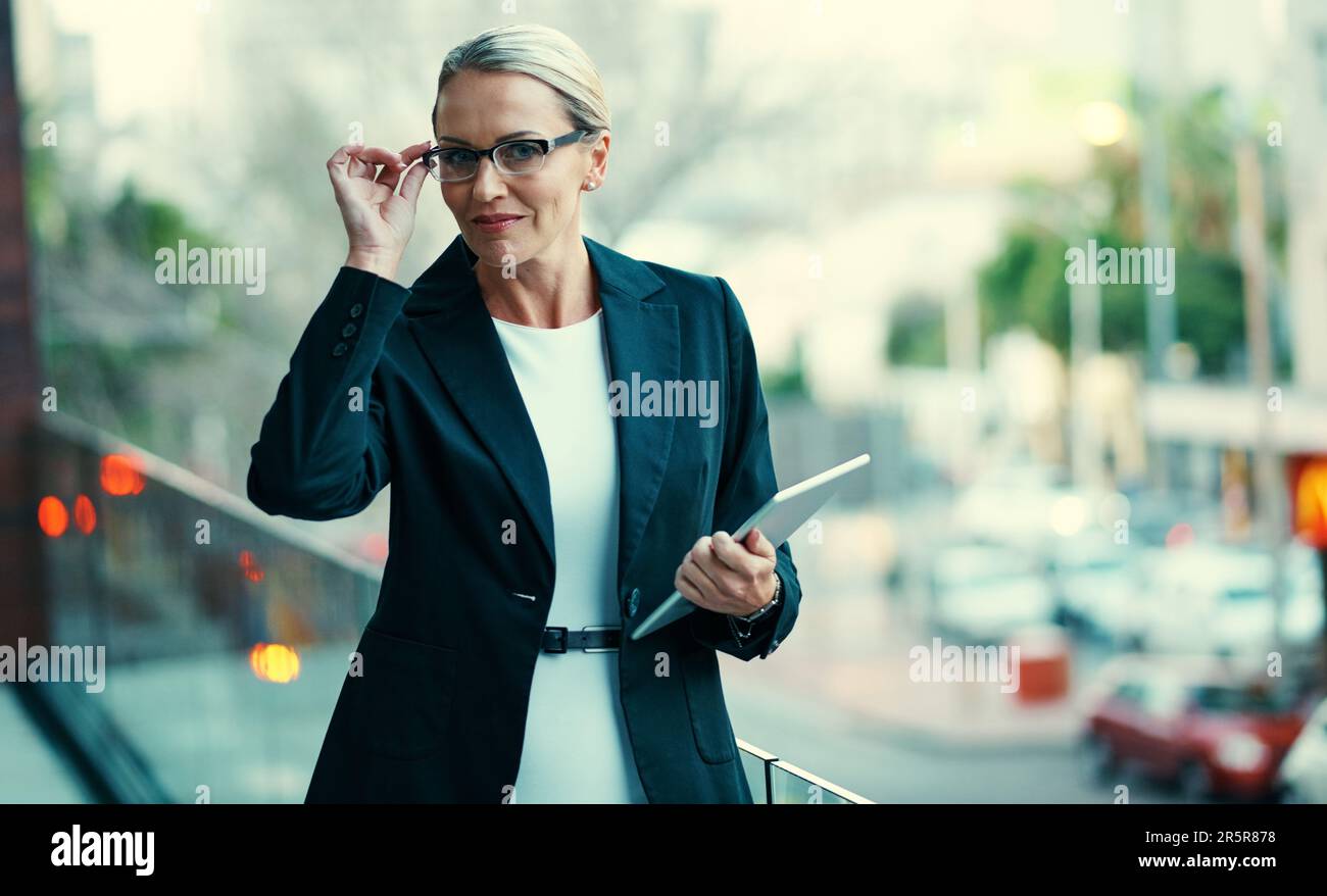 Il successo hanno visione. Ritratto di una donna d'affari matura in piedi fuori sul balcone di un ufficio e tenendo un tablet digitale. Foto Stock