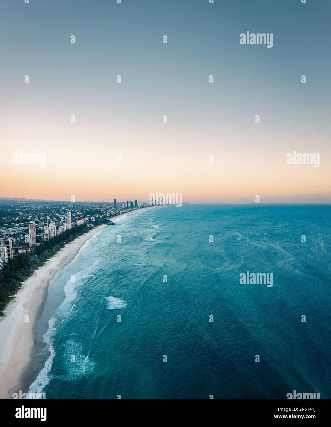 Un'immagine di una spiaggia di sabbia con l'oceano sullo sfondo e alti edifici in lontananza Foto Stock