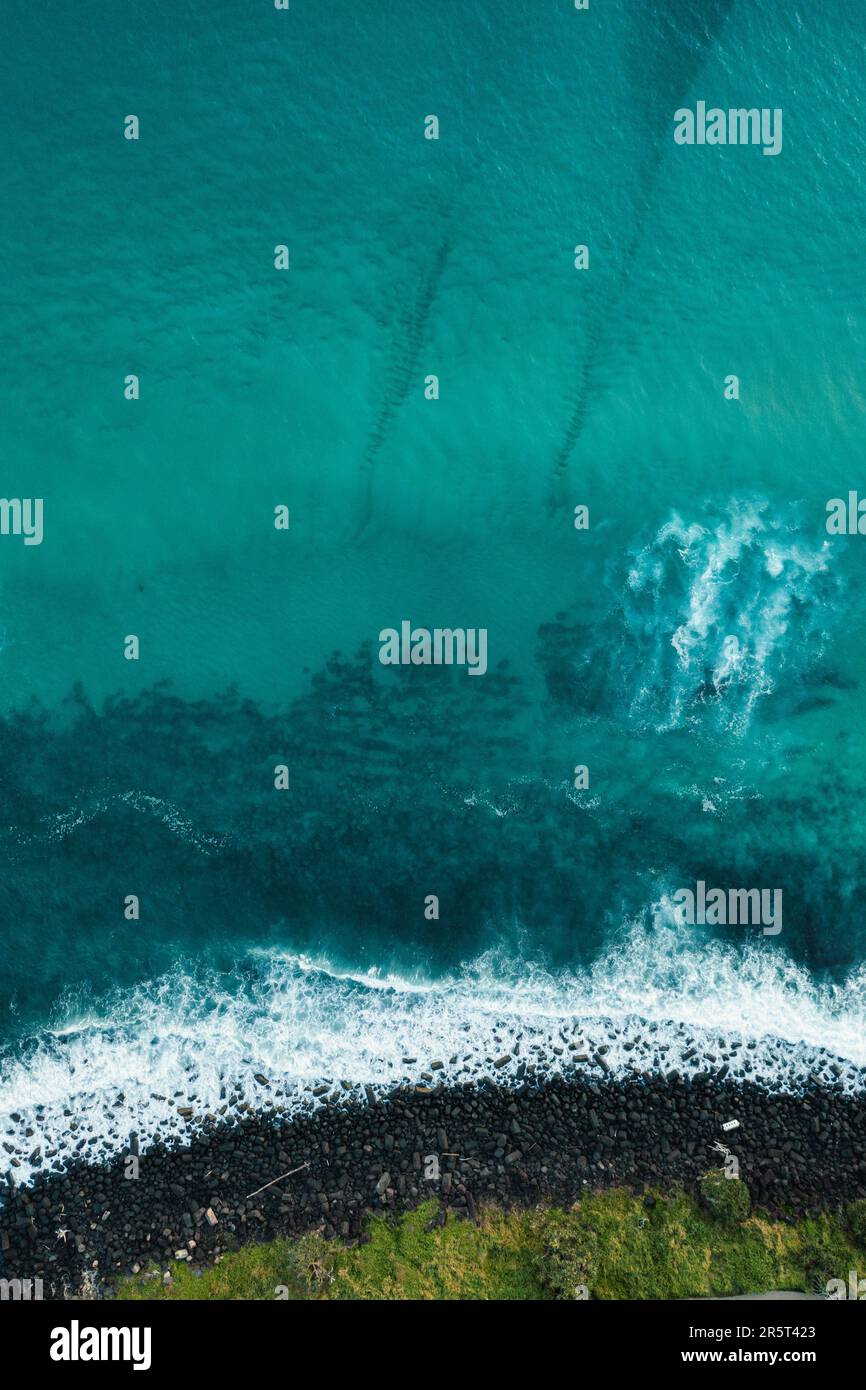 Due tavole da surf sono state cavalcate in una grande onda dell'oceano vicino a una scogliera rocciosa Foto Stock