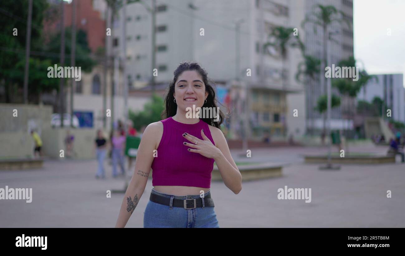 Una giovane donna sicura in piedi all'aperto in città battendo il petto sensazione di fiducia Foto Stock