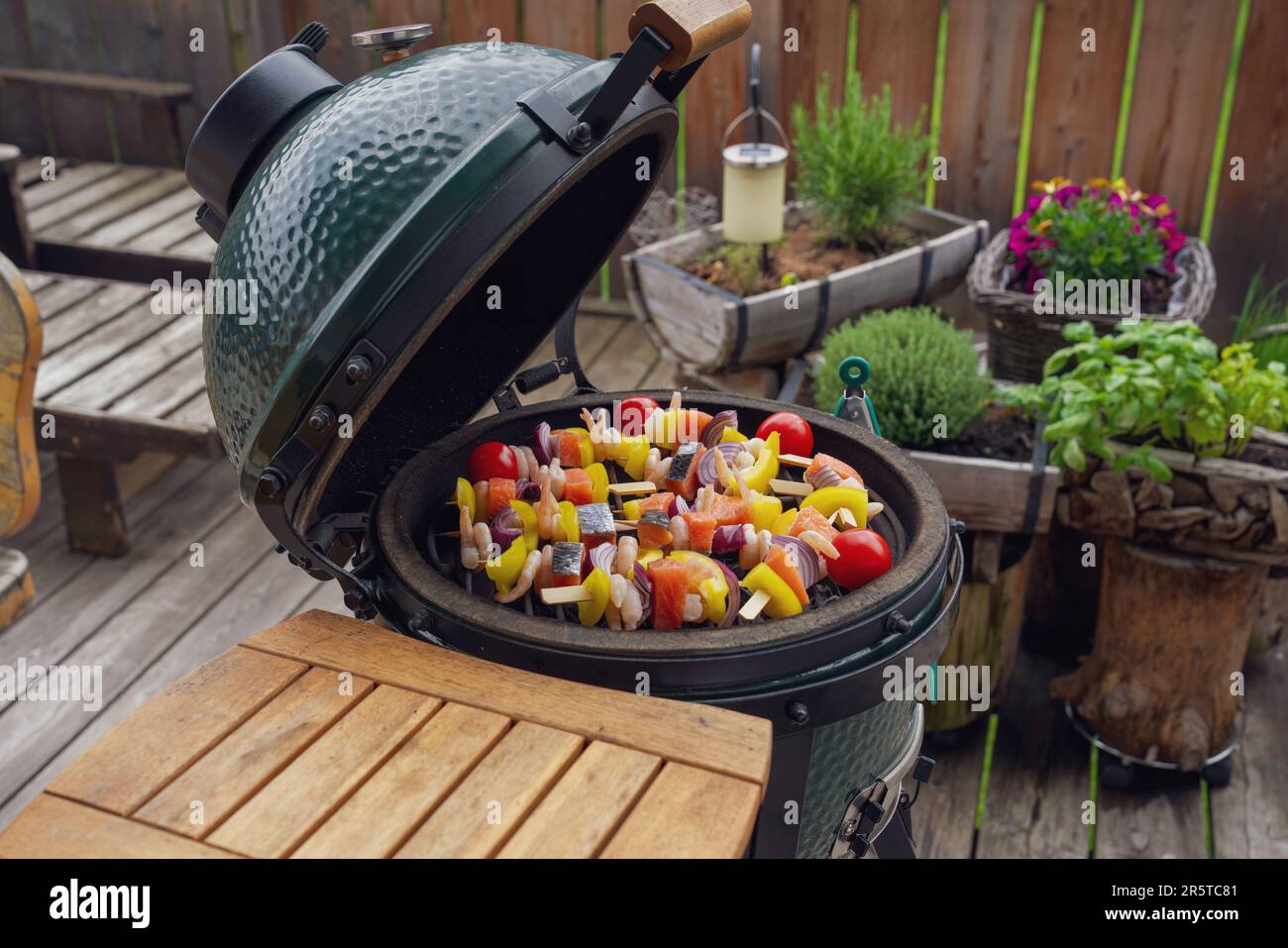 spiedini di gamberetti crudi grigliati con salmone e verdure per grigliare su una griglia a carbone sul balcone in una giornata estiva Foto Stock