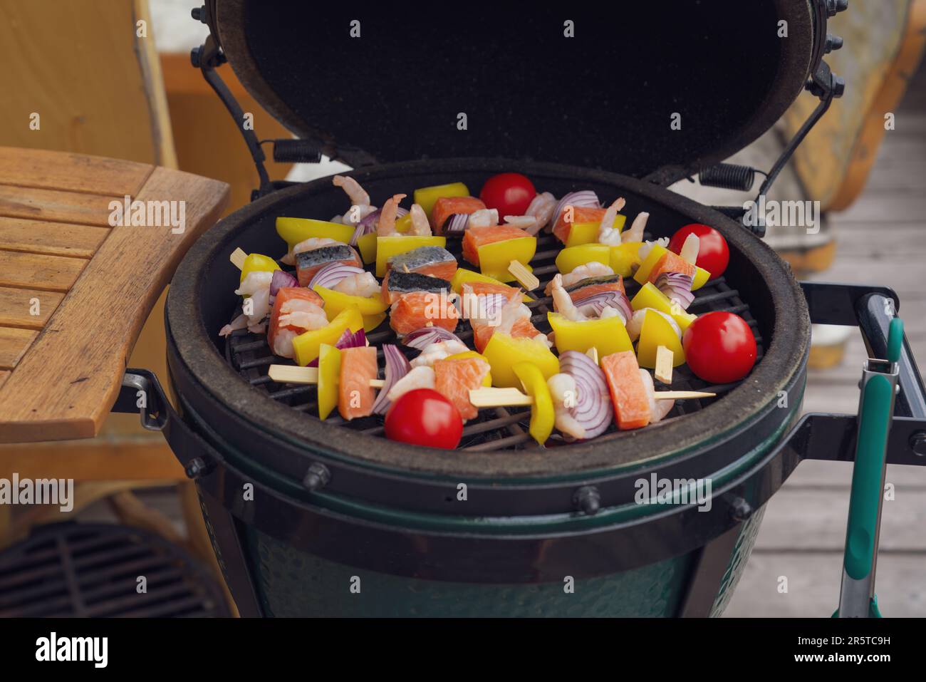 spiedini di gamberetti crudi grigliati con salmone e verdure per grigliare su una griglia a carbone sul balcone in una giornata estiva Foto Stock