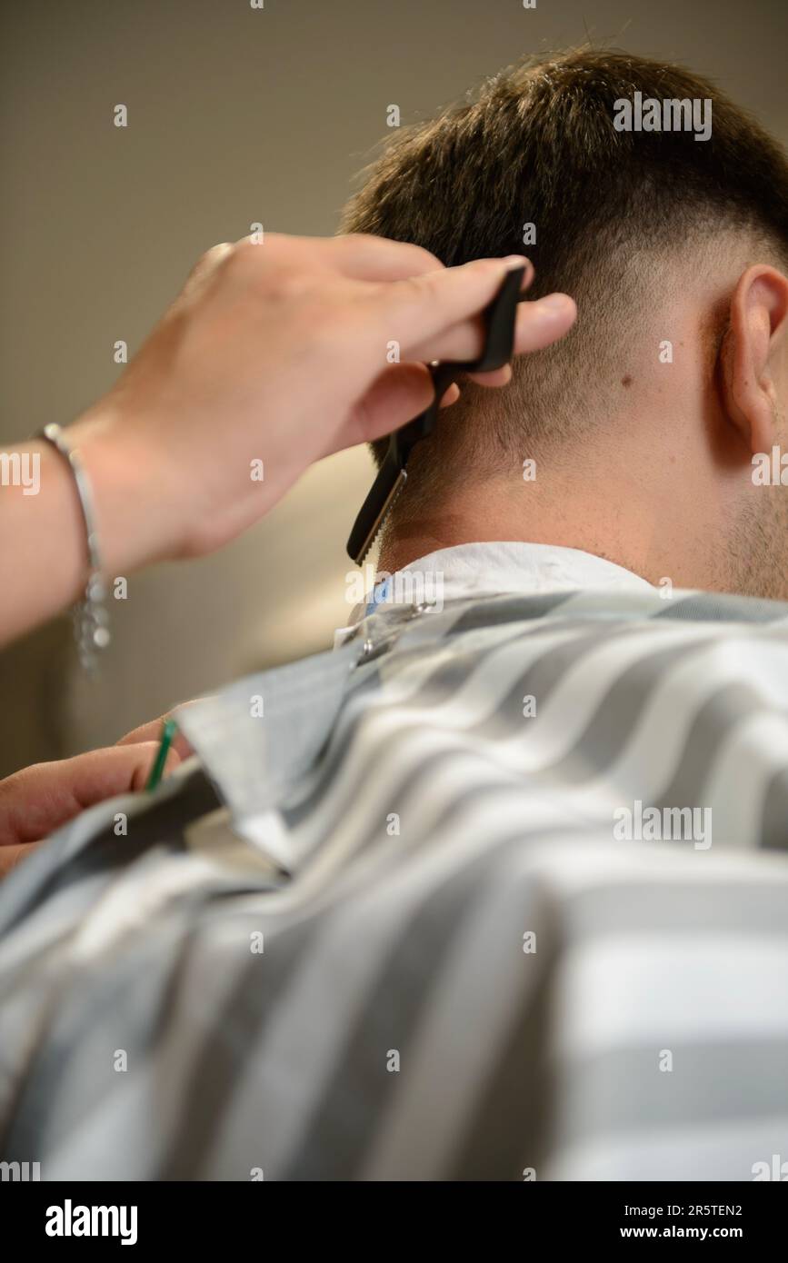 Uomo che ottiene un taglio di capelli con una forbice al barbiere Foto Stock