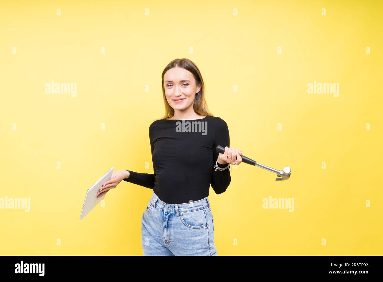 Centro servizi. Riparazione del notebook. Il cacciavite femmina svita i bulloni del computer portatile su sfondo giallo Foto Stock