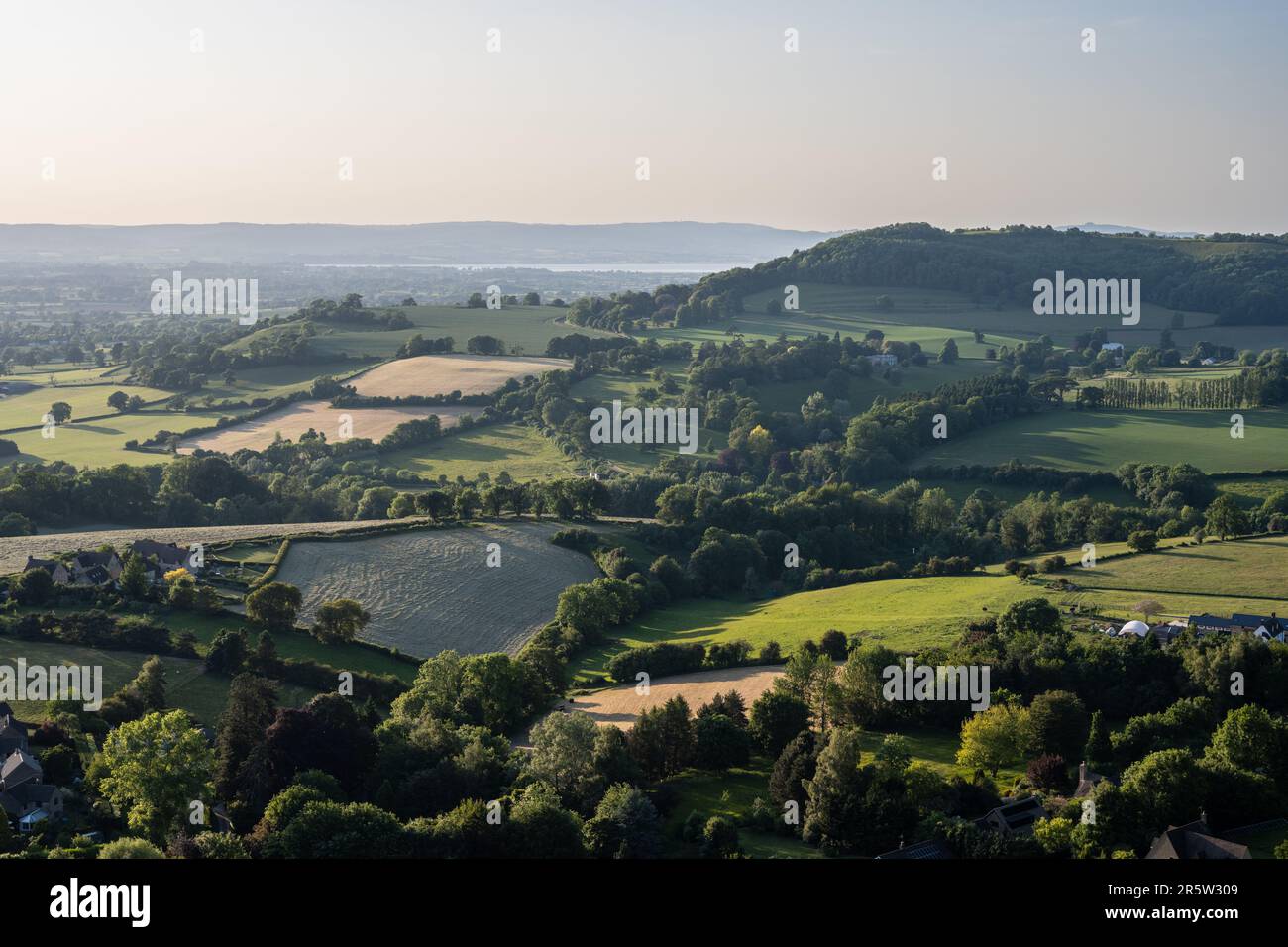 Il sole serale splende sul paesaggio pastorale della valle di Severn sotto il margine di Cotswolds a Nibley nord nel Gloucestershire, con l'estuario di Severn Foto Stock