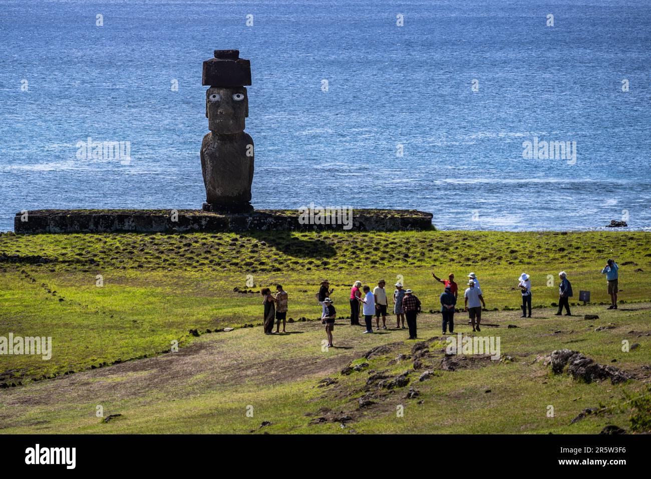 Isola di Pasqua, Cile -- 25 gennaio 2023.. Foto di una statua di Moai rivolta verso l'interno mentre il gruppo del tour passa; l'oceano Pacifico è sullo sfondo. Foto Stock