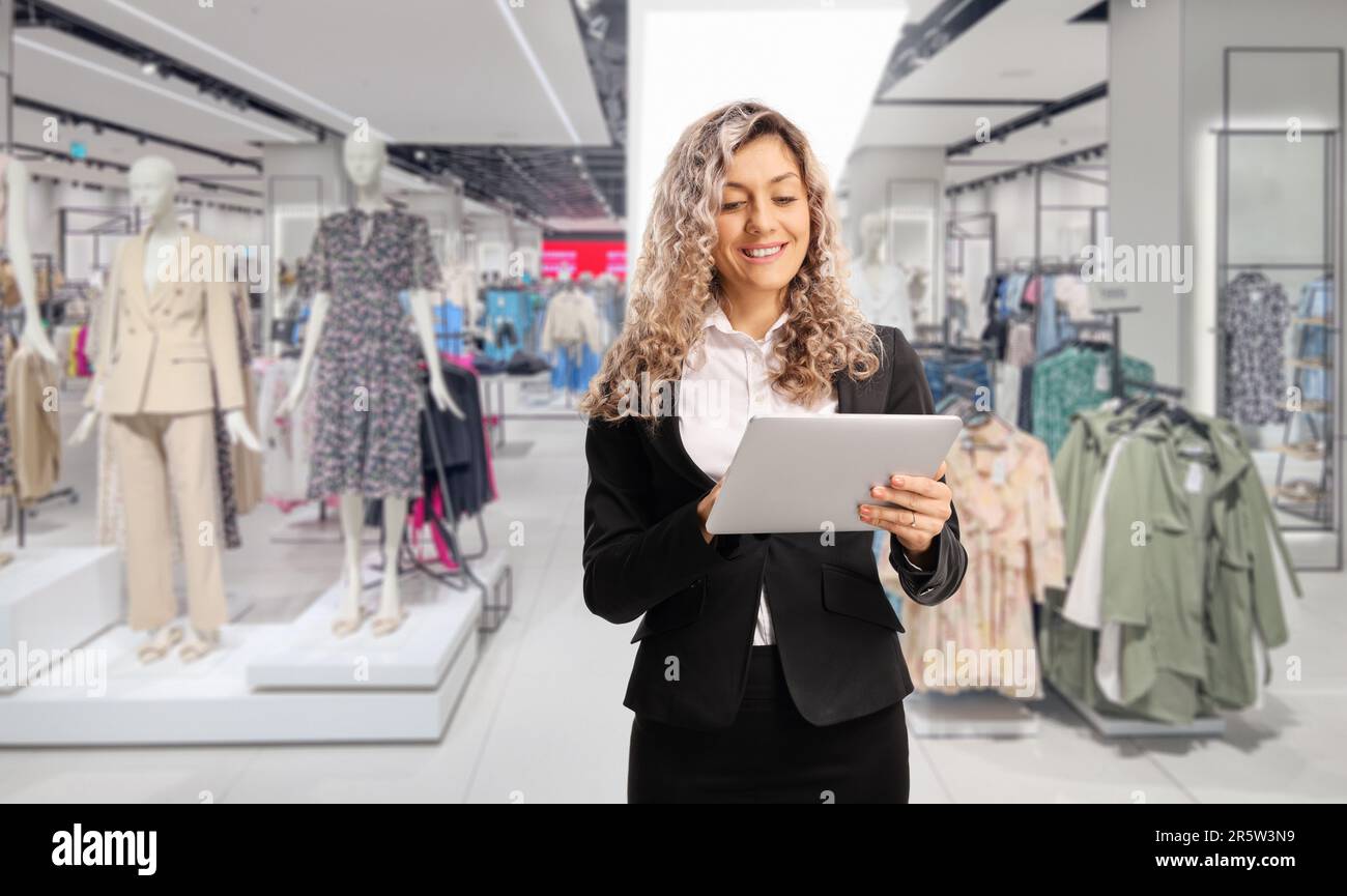 Donna d'affari che utilizza un tablet digitale all'interno di un negozio di abbigliamento Foto Stock