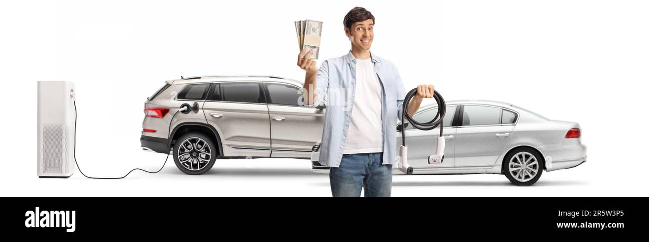 Uomo che tiene un cavo per la ricarica di veicoli elettrici e pile di denaro in una stazione di ricarica isolata su sfondo bianco Foto Stock