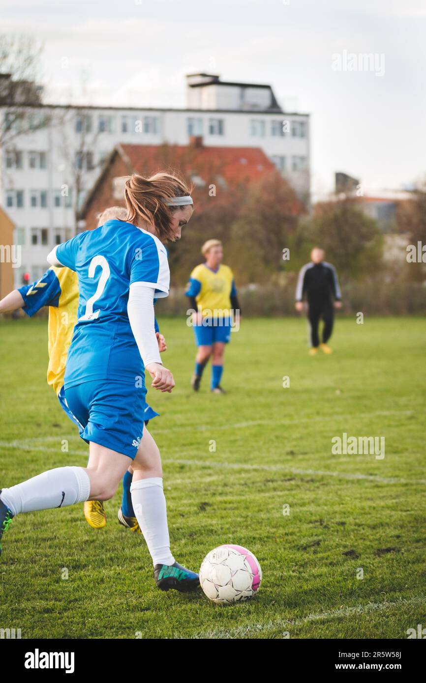Un'atleta femminile sta giocando a calcio su un campo erboso mentre molti  altri giocatori guardano sopra Foto stock - Alamy