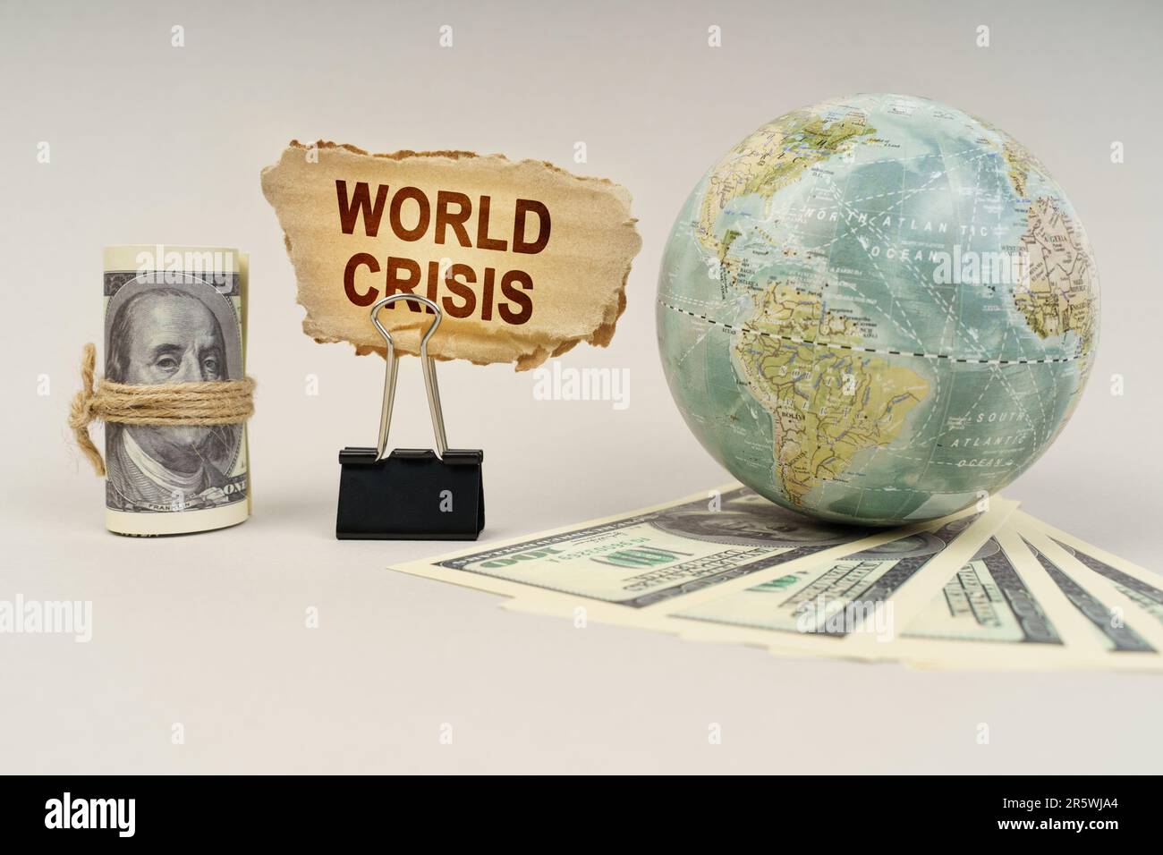 Concetto di business e finanza. Sul tavolo ci sono i dollari, un globo e c'è un segno con l'iscrizione - crisi mondiale Foto Stock